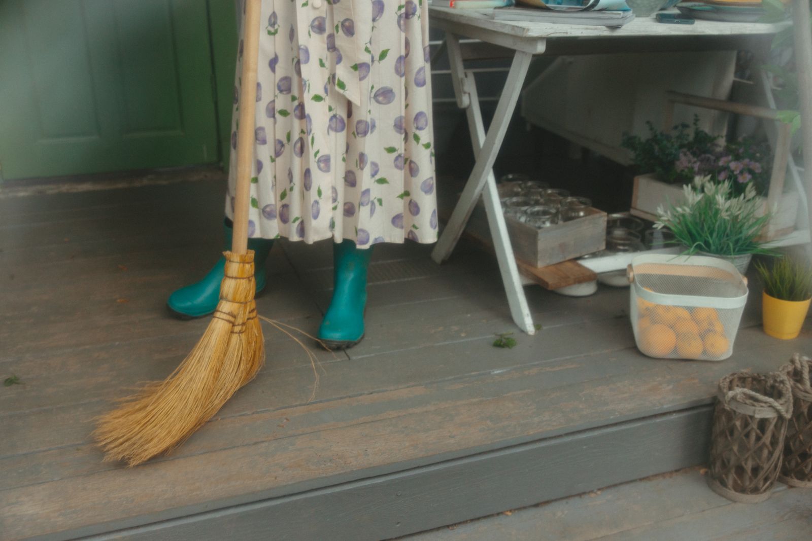 Someone sweeping a porch beside potted plants